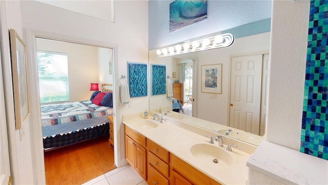 bathroom with tile patterned flooring, a sink, ensuite bath, and double vanity