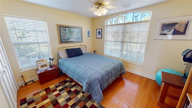 bedroom featuring baseboards, multiple windows, and hardwood / wood-style floors