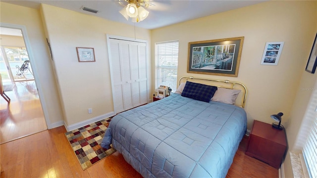 bedroom featuring a closet, visible vents, a ceiling fan, wood finished floors, and baseboards