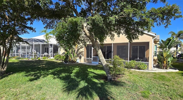 back of property featuring a lanai, a lawn, and stucco siding