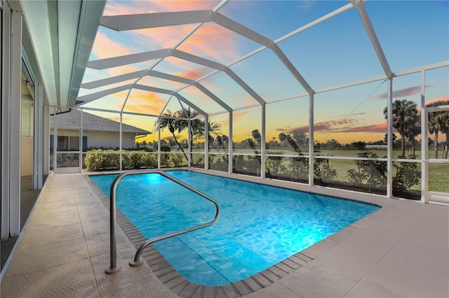 pool at dusk with glass enclosure, a patio, and an outdoor pool