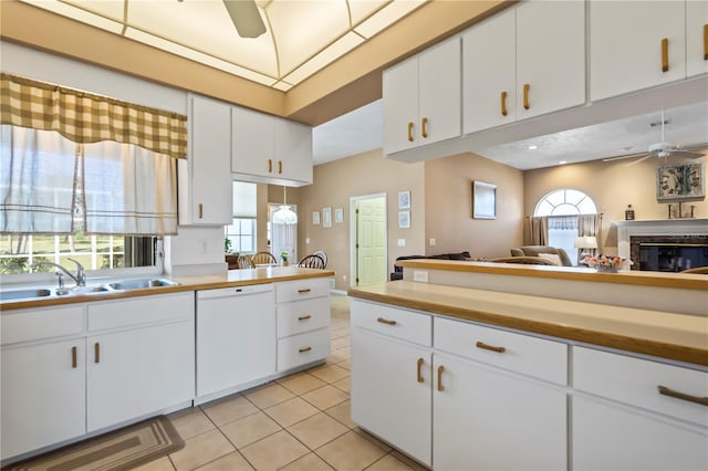 kitchen with ceiling fan, light tile patterned floors, a sink, open floor plan, and dishwasher