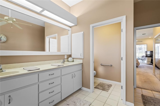 ensuite bathroom featuring ceiling fan, double vanity, a sink, and toilet