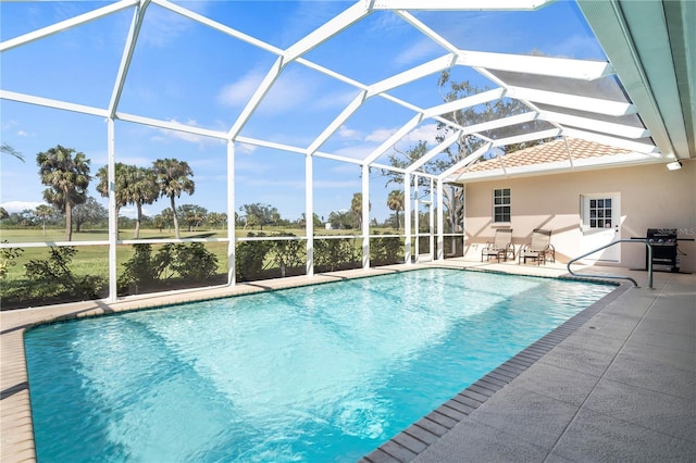 outdoor pool with grilling area, a patio area, and a lanai