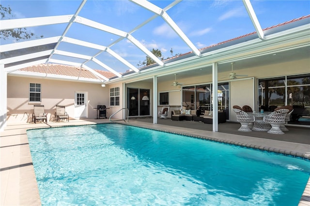 pool featuring outdoor lounge area, grilling area, a ceiling fan, glass enclosure, and a patio area