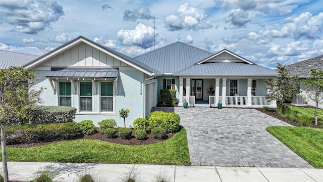 view of front facade with metal roof, a porch, board and batten siding, and decorative driveway