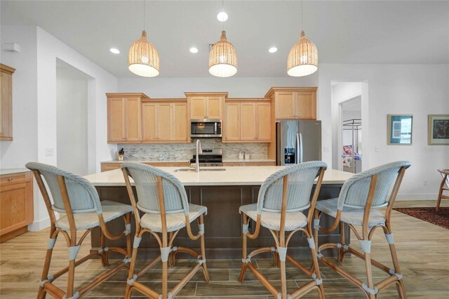 42239 Lake Timber Dr, Punta Gorda, FL 33982 - kitchen with decorative backsplash, a kitchen island with sink, stainless steel appliances, light countertops, and light wood-type flooring