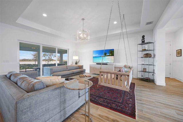 42239 Lake Timber Dr, Punta Gorda, FL 33982 - living room with wood finish floors, a raised ceiling, visible vents, a chandelier, and baseboards