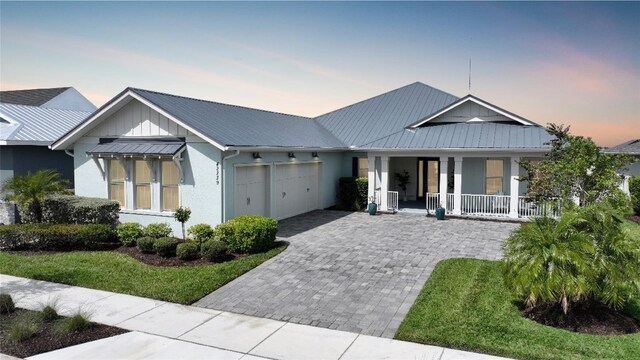 42239 Lake Timber Dr, Punta Gorda, FL 33982 - view of front of house featuring decorative driveway, a porch, an attached garage, a standing seam roof, and metal roof