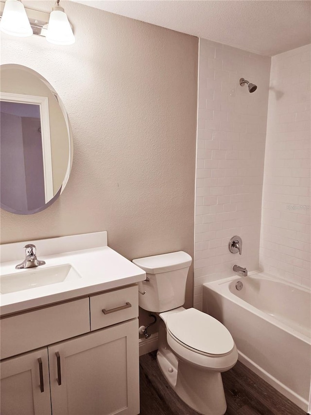 bathroom with shower / bath combination, toilet, a textured ceiling, vanity, and wood finished floors