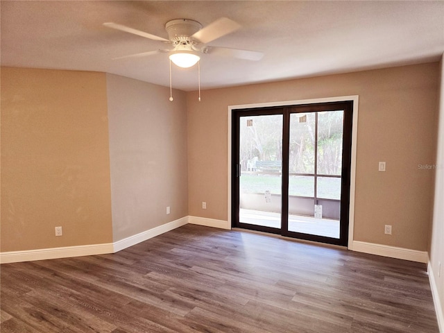 spare room with dark wood-style floors, baseboards, and a ceiling fan