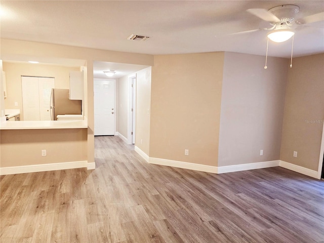 spare room with ceiling fan, wood finished floors, visible vents, and baseboards