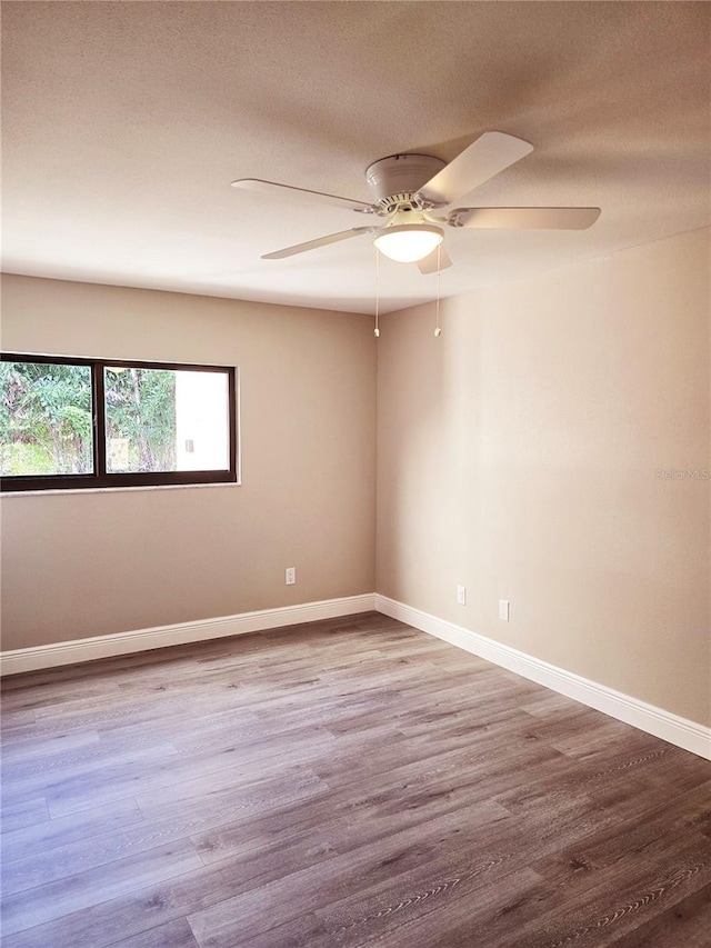 spare room with ceiling fan, a textured ceiling, baseboards, and wood finished floors