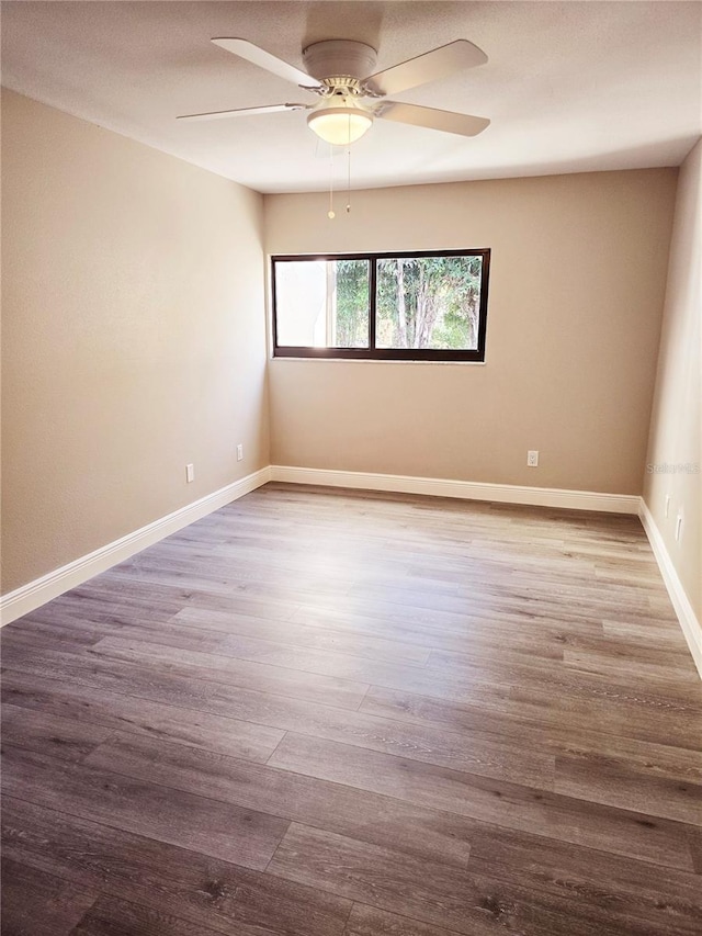 empty room with ceiling fan, baseboards, and wood finished floors