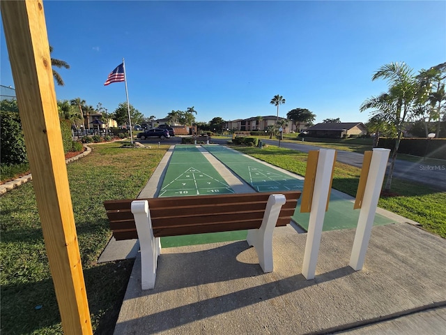 view of property's community featuring shuffleboard and a lawn