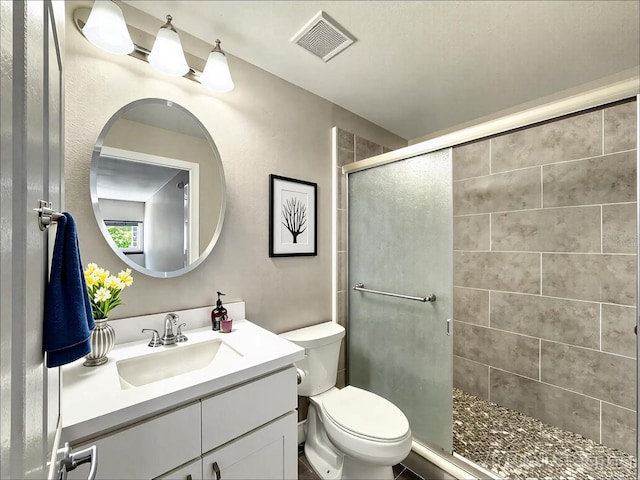 bathroom featuring visible vents, vanity, toilet, and a shower stall
