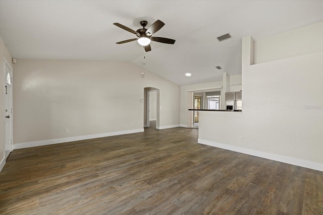 unfurnished living room featuring dark wood-style floors, arched walkways, lofted ceiling, visible vents, and a ceiling fan