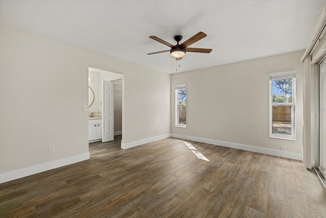 unfurnished bedroom with ensuite bathroom, ceiling fan, wood finished floors, and baseboards