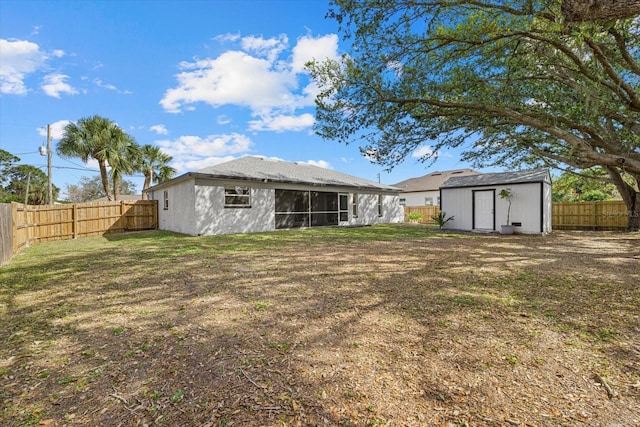 rear view of property featuring a fenced backyard, a shed, a lawn, and an outbuilding