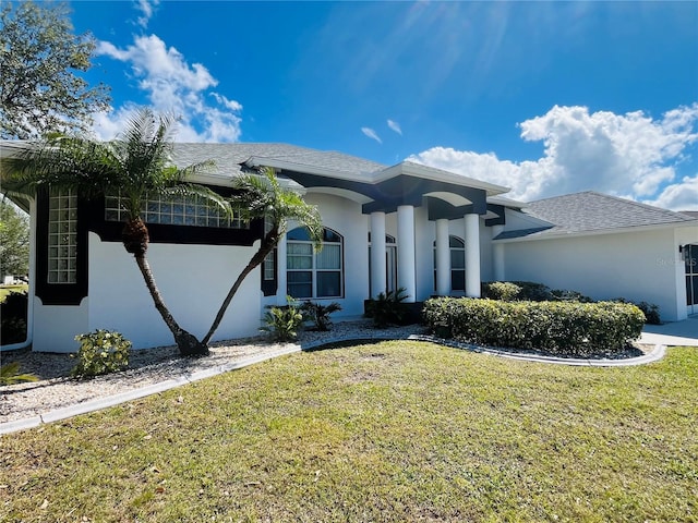 view of front of home featuring a shingled roof, a front lawn, and stucco siding