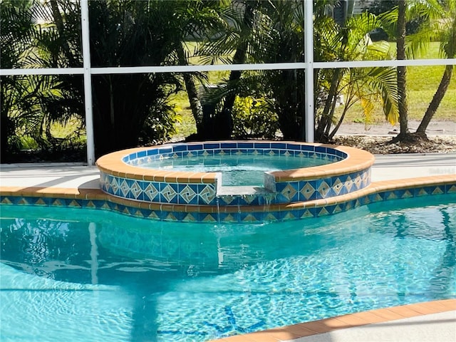 view of pool with glass enclosure and a pool with connected hot tub