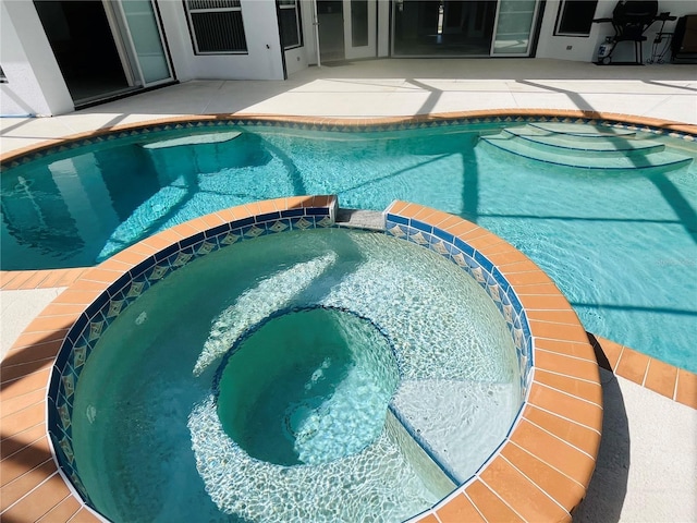 view of pool featuring a patio area and a pool with connected hot tub