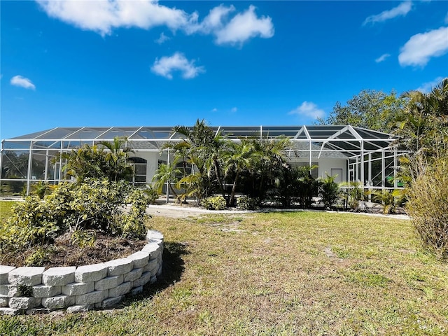 rear view of house featuring glass enclosure and a lawn