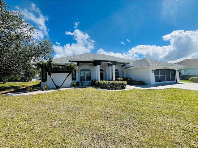 view of front of home featuring an attached garage, driveway, a front yard, and stucco siding