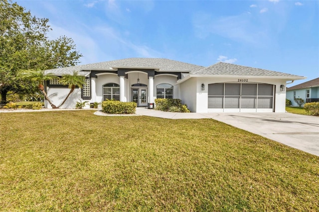 view of front of house featuring an attached garage, driveway, french doors, stucco siding, and a front yard