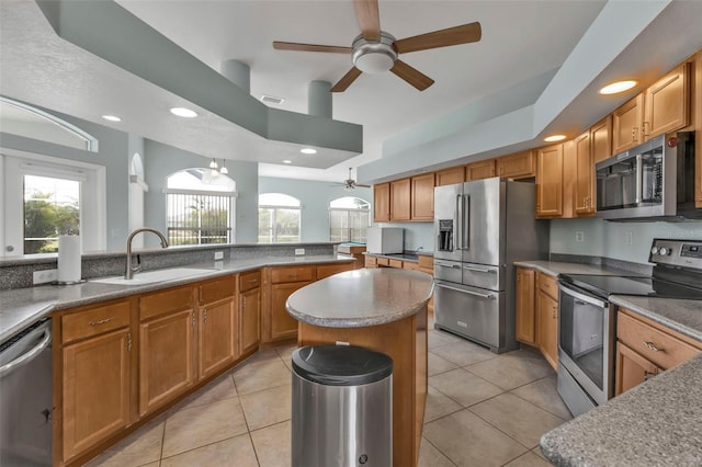 kitchen with appliances with stainless steel finishes, brown cabinets, light tile patterned flooring, and a sink