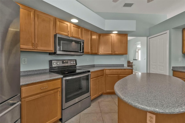 kitchen with light tile patterned flooring, recessed lighting, a kitchen island, visible vents, and appliances with stainless steel finishes