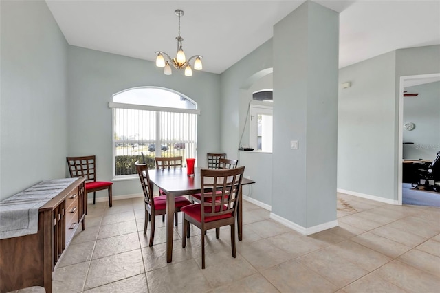 dining room with light tile patterned floors, baseboards, a chandelier, and arched walkways