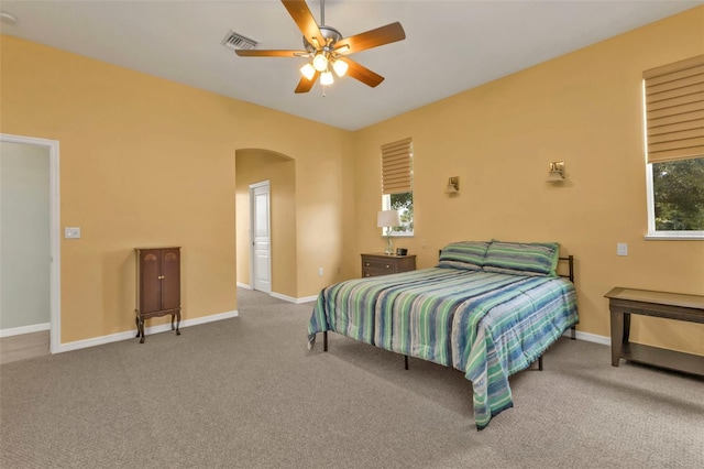 bedroom featuring arched walkways, a ceiling fan, visible vents, baseboards, and carpet