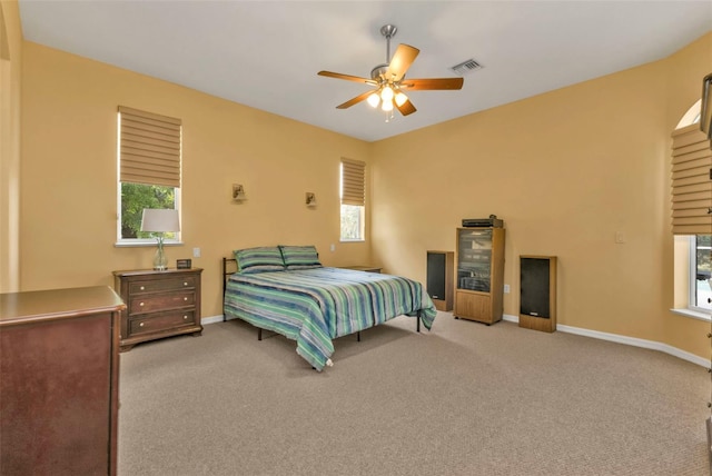 carpeted bedroom featuring baseboards, multiple windows, visible vents, and a ceiling fan