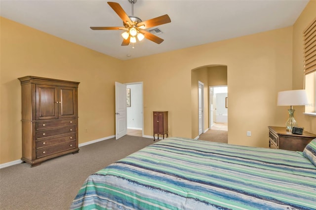 carpeted bedroom with arched walkways, visible vents, ensuite bathroom, a ceiling fan, and baseboards