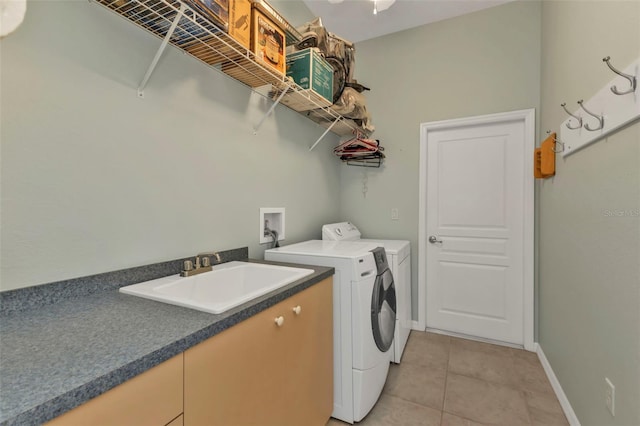 clothes washing area featuring laundry area, baseboards, washer and dryer, a sink, and light tile patterned flooring