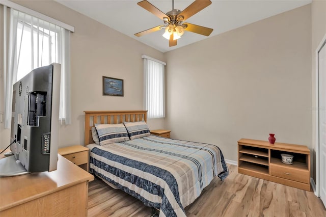 bedroom with ceiling fan, light wood finished floors, and baseboards