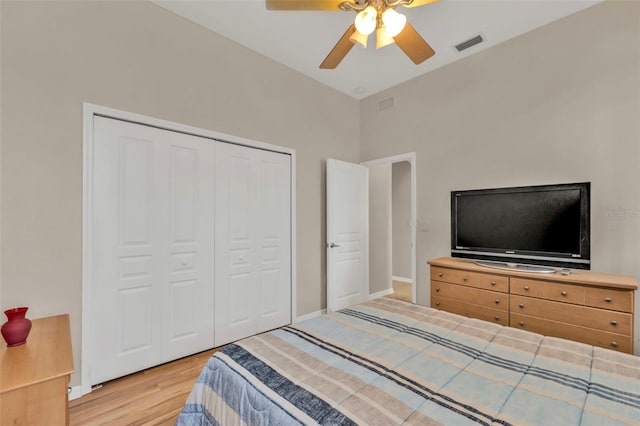 bedroom with a closet, wood finished floors, visible vents, and baseboards