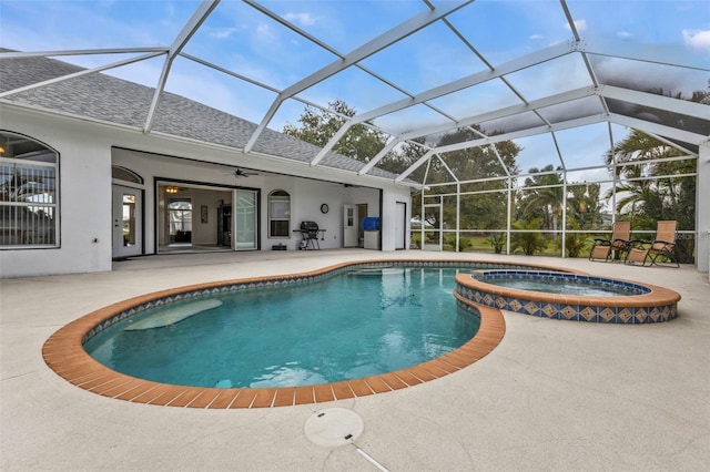 view of pool featuring glass enclosure, a pool with connected hot tub, and a patio