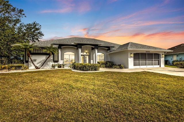 view of front of home with an attached garage, a lawn, concrete driveway, and stucco siding