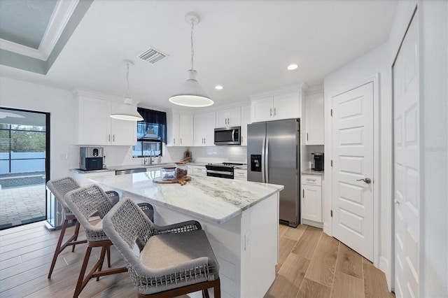 14325 Mcfarland Ave, Port Charlotte, FL 33981 - kitchen with stainless steel appliances, a kitchen island, a breakfast bar, white cabinets, and recessed lighting