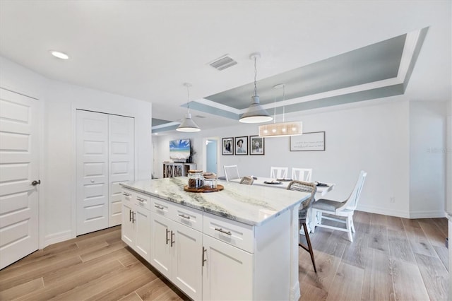 14325 Mcfarland Ave, Port Charlotte, FL 33981 - kitchen featuring a raised ceiling, white cabinetry, light wood-type flooring, a center island, and pendant lighting