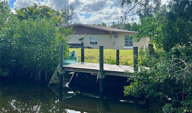 view of side of property with a yard, a dock, and stucco siding