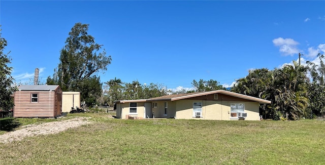 back of house featuring an outbuilding, a lawn, and stucco siding