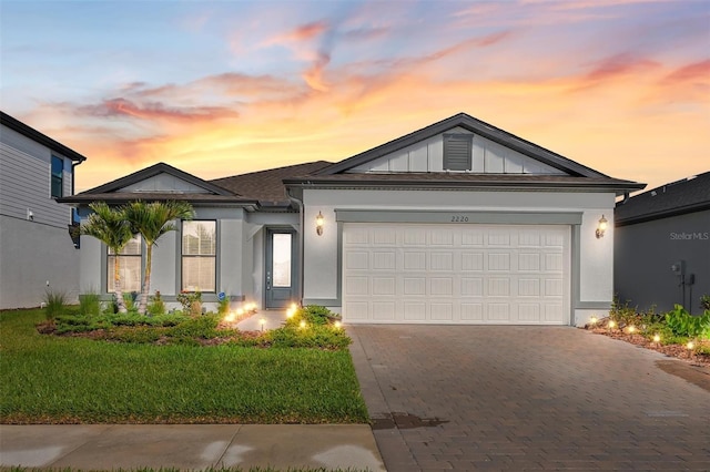 ranch-style house with an attached garage, decorative driveway, and stucco siding