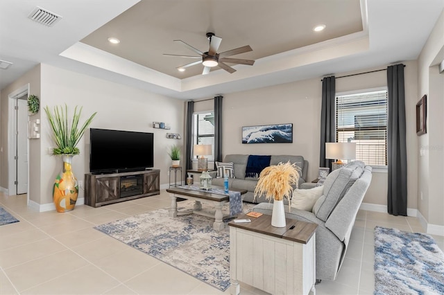 living area with a tray ceiling, light tile patterned flooring, and visible vents