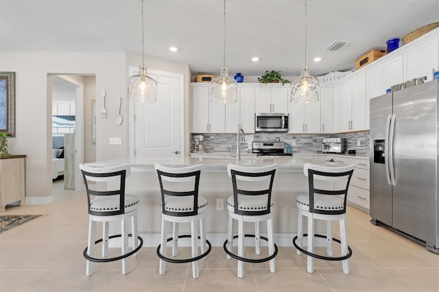 kitchen with light tile patterned flooring, white cabinetry, light countertops, appliances with stainless steel finishes, and decorative backsplash