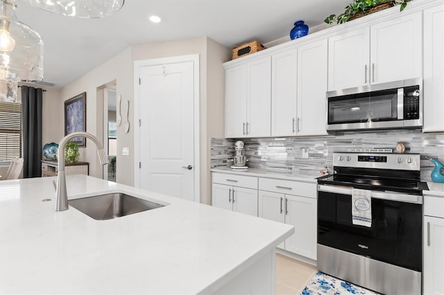 kitchen with decorative backsplash, stainless steel appliances, light countertops, white cabinetry, and a sink