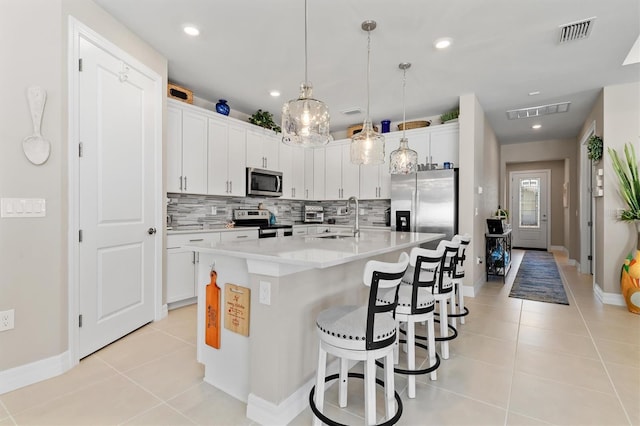 kitchen with light tile patterned floors, stainless steel appliances, tasteful backsplash, visible vents, and a sink