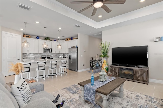 living area with light tile patterned floors, visible vents, a raised ceiling, ornamental molding, and recessed lighting